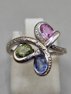 une photo en gros plan d'une bague ornée de trois pierres de couleurs différentes