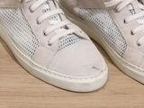 a close up of a pair of white sneakers on a wooden floor