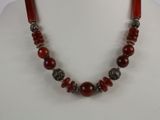 a close up of a necklace with red beads on a mannequin