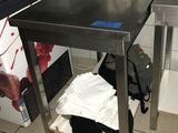 une table en acier inoxydable sur laquelle est posé un ordinateur portable, dans une cuisine
