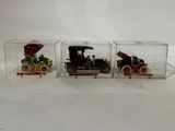 three small toy cars in a glass case