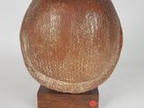 a brown vase sitting on a wooden stand on a white surface