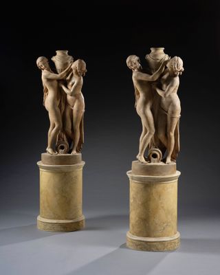 pair of marble sculptures of a woman and a man on pedestals