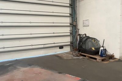 un sac noir posé sur une palette devant la porte d'un garage