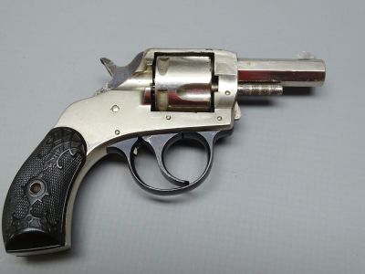 un revolver argenté à la crosse noire posé sur une table blanche
