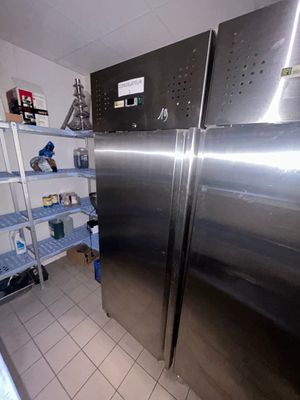 un grand réfrigérateur en acier inoxydable dans une cuisine, à côté d'étagères