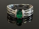 a close up of a ring with a green stone on a black surface