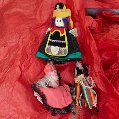 two dolls that are laying on a red sheet