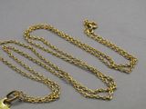 a close up of a gold necklace with a chain on a gray surface