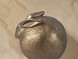 sculpture of a golden apple with a leaf on top of a wooden stand