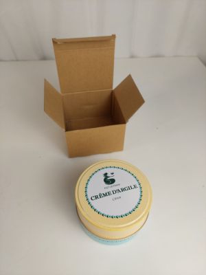 une petite boîte avec un couvercle et un petit récipient posés sur une table