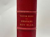 an old red book sitting on top of a white table