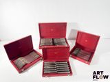 three red boxes with silverware in them sitting on a white surface