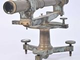 un télescope d'aspect très ancien posé sur un trépied, sur une surface blanche