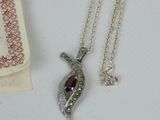 a silver necklace with a red stone on it next to a book