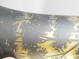 une personne tenant un vase noir orné de motifs dorés