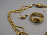un collier, une bague et une boucle d'oreille en or posés sur une table
