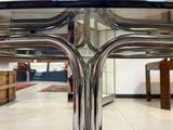 une table en verre avec un piètement en métal au milieu d'une pièce