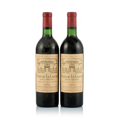 two bottles of red wine sitting next to each other on a white surface