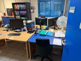 un bureau avec deux ordinateurs et un ventilateur dans un coin