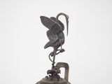 a bronze bell with a bird on top of it