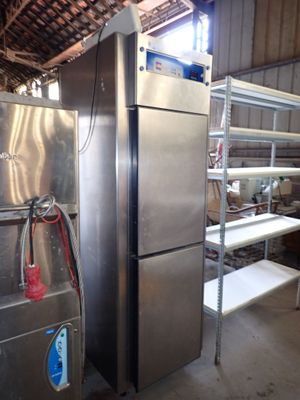 stainless steel refrigerator in a warehouse with shelves and shelves on either side of the refrigerator