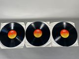 three black vinyl records sitting on top of each other on a white surface