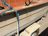 a boat tied up to a trailer on the side of the road