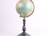 un vieux globe terrestre posé sur un socle, avec un fond blanc