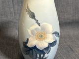 un vase blanc orné d'une fleur sur fond gris