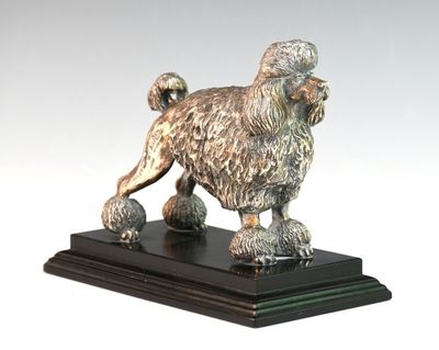 statue d'un caniche posée sur un socle noir, sur fond blanc