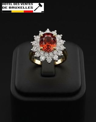 a close up of a ring with a red stone surrounded by white diamonds
