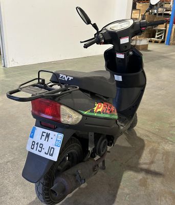un scooter garé dans un garage, avec une plaque d'immatriculation à l'arrière