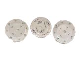 trois assiettes blanches ornées de motifs floraux, disposées les unes à côté des autres