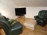 a living room with two green leather chairs and a television