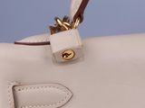 the handle of a white purse with a gold clasp