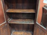 une armoire en bois dont la porte est ouverte, posée sur un sol carrelé