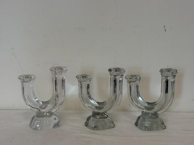 trois bougeoirs en verre posés sur une table, avec un mur blanc en arrière-plan