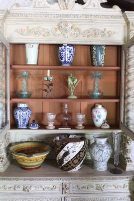 many vases and bowls on a shelf in a cabinet