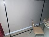 an image of a room with a clothes rack and a chair