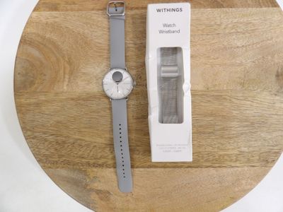 a white watch sitting on top of a wooden table next to a box