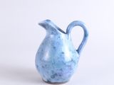 a small blue vase with a handle on a white surface