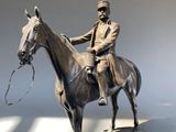 a statue of a man riding a horse with a rope