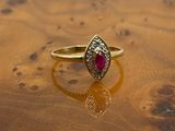 yellow gold ring with ruby and diamonds on a wooden surface