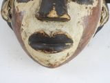 a close up of a wooden mask on a white surface