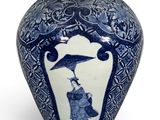 un vase bleu et blanc surmonté d'un oiseau