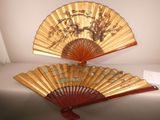 pair of oriental fans with flowers and birds on them on a table