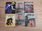 four books on a wooden floor, one of which has a picture of a man on a horse