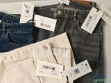 three pairs of jeans with price tags on them sitting on a table