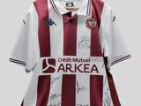 un gros plan sur un maillot de foot sur lequel figurent les signatures des joueurs